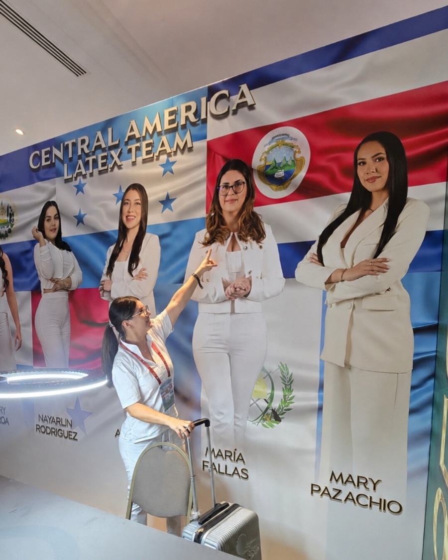 María Fallas junto al mural del Central America Latex Team, señalando su fotografía bajo la bandera de Costa Rica